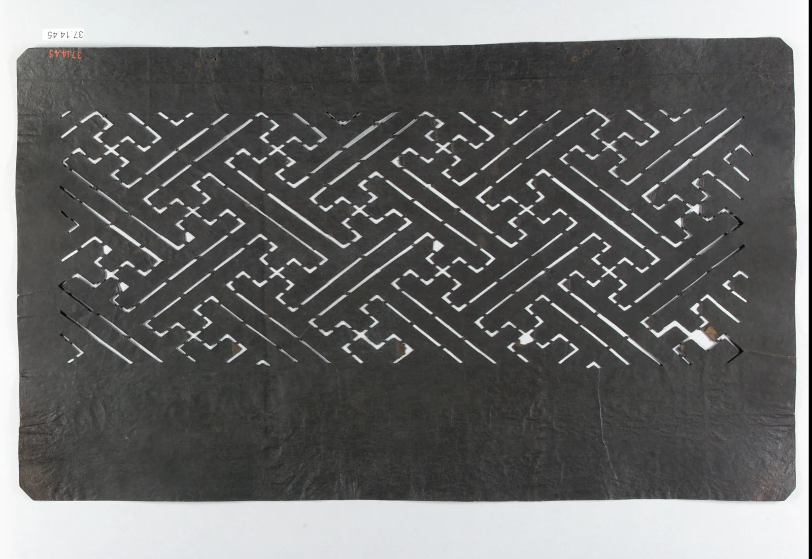 A carved paper dye stencil with a continuous sayagata fret pattern