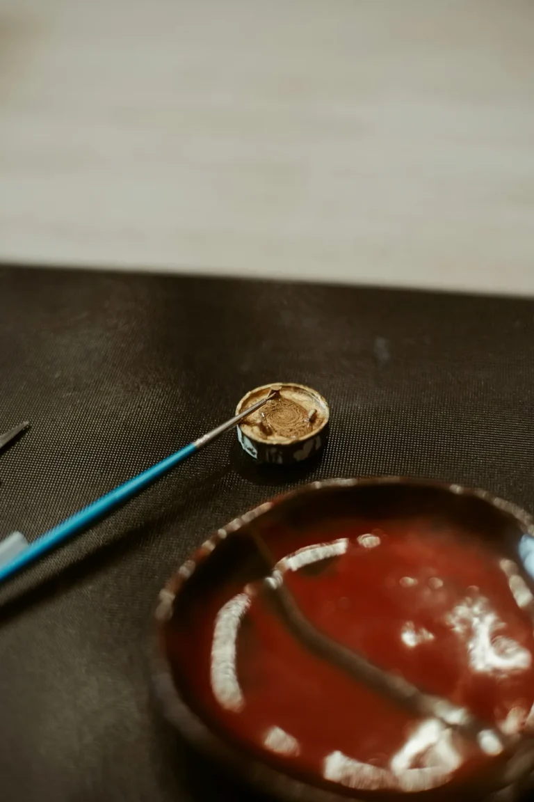 Paintbrush in a container near a painted bowl