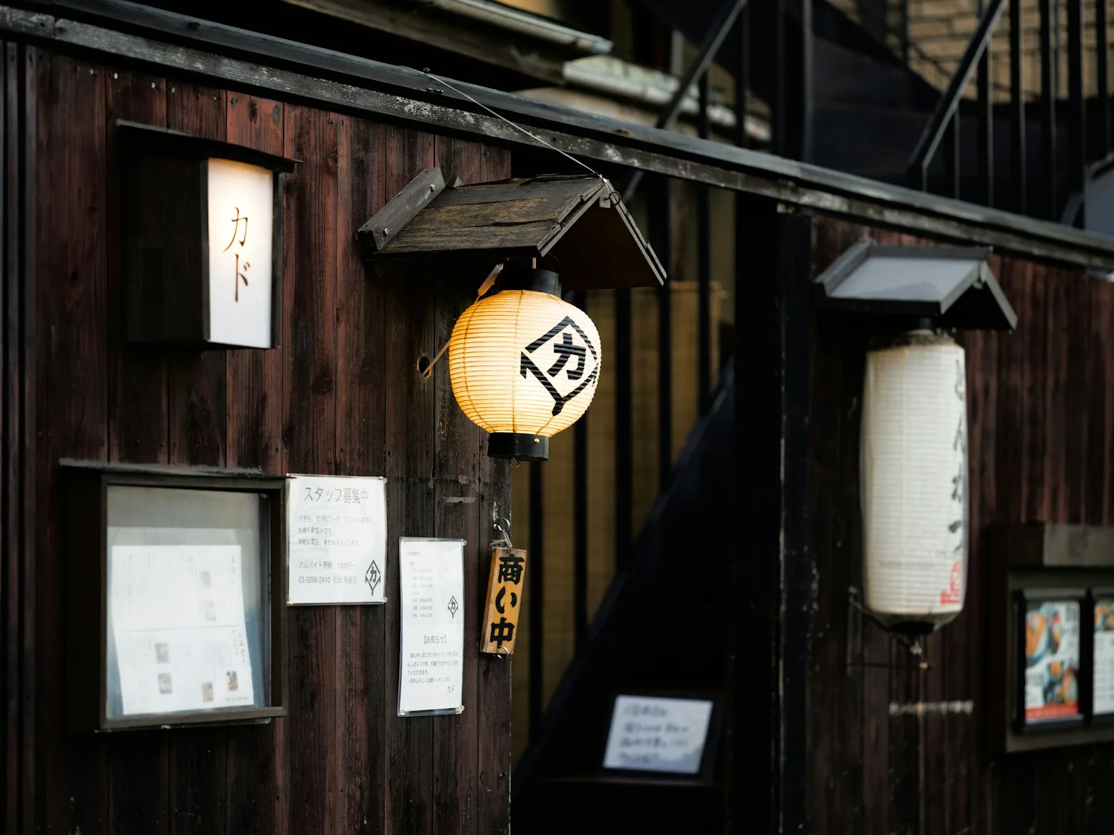 Japanese paper lanterns illuminate a traditional wooden building exterior