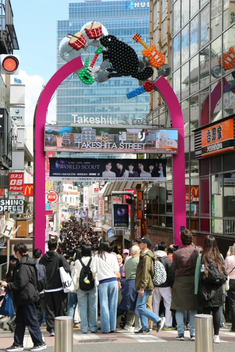 Crowded street under a pink archway with music decorations