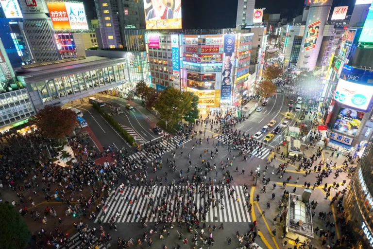 Crowds of people crossing the Shibuya scramble intersection at night in Tokyo